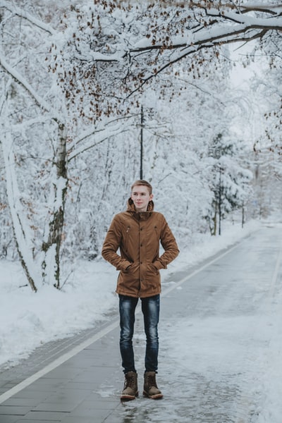 身穿棕色夹克的男子站在积雪覆盖的地面上